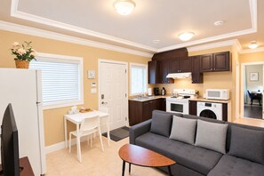 A compact living space with a kitchenette, a sofa, a dining table, and a TV.