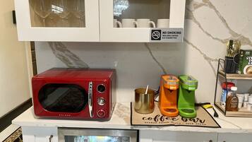 A kitchen with a red microwave, a coffee machine, and a coffee bar sign.