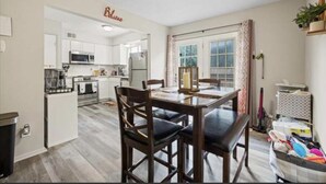 A compact kitchen with white cabinets, a microwave, and a refrigerator. There is a dining area with a table and chairs. - Two bedroom condo for rent! (Columbus)