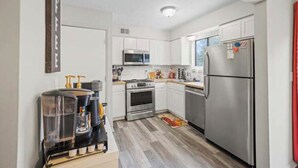 A compact kitchen with white cabinets, stainless steel appliances, and a coffee machine. - Two bedroom condo for rent! (Columbus)
