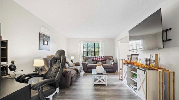 A modern living room with a gaming chair, a sofa, a coffee table, and a TV mounted on the wall. - Two bedroom condo for rent! (Columbus)