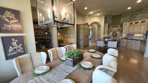 Un espace repas avec une longue table dressée pour six personnes, entourée de chaises rembourrées.