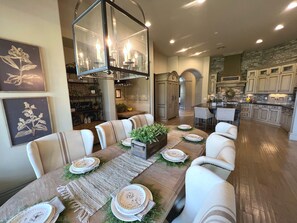 Un espace repas avec une longue table dressée pour six personnes, entourée de chaises rembourrées.