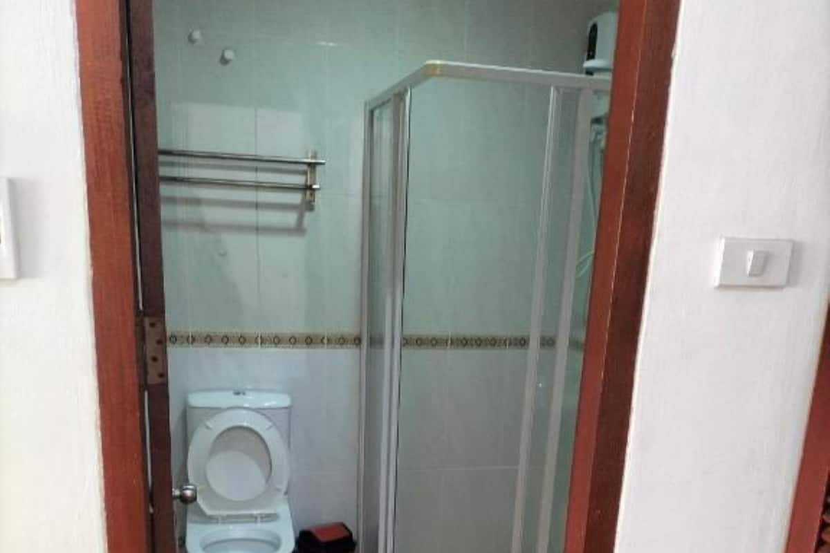 A bathroom with a toilet, a shower enclosure, and a tiled floor.