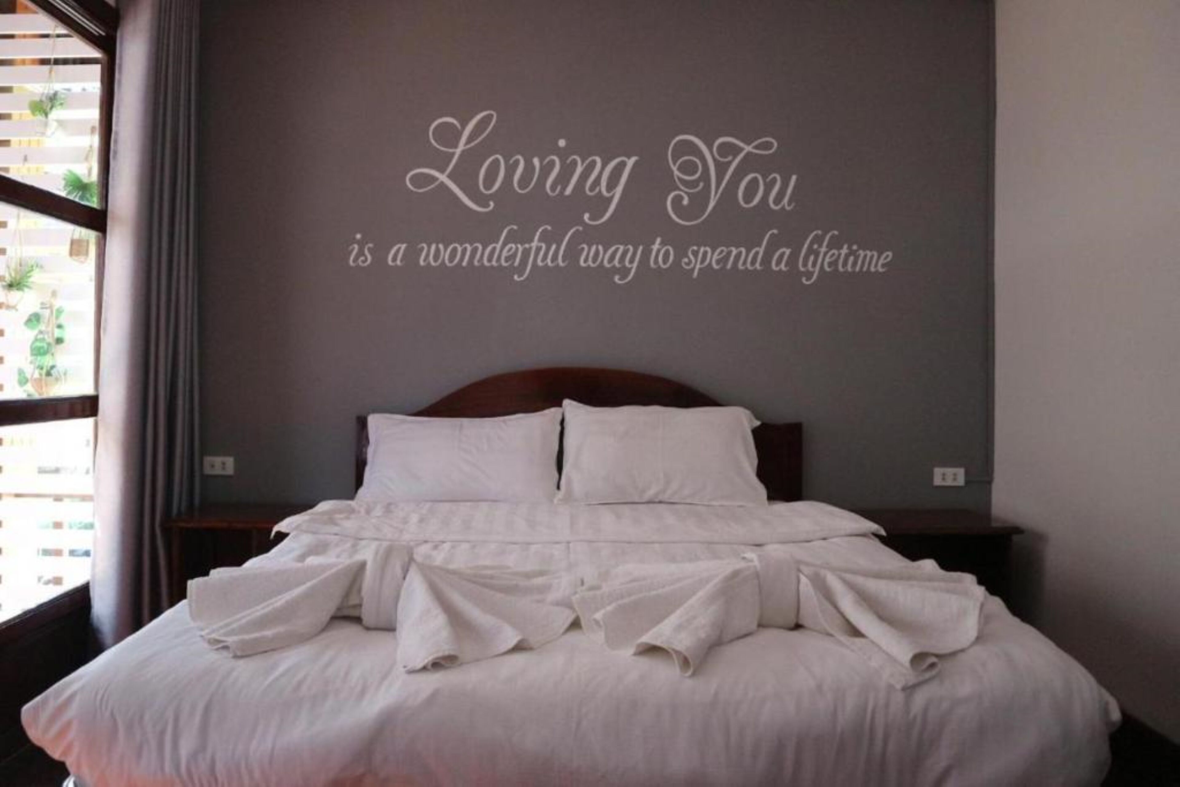 A neatly made bed with white linens and towels arranged on the bed.