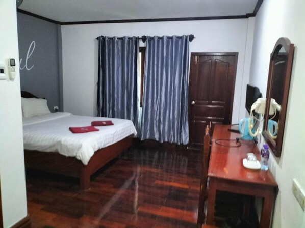A bedroom with a bed, a wooden desk, a mirror, and a door. - DaViKa Hotel (Vientiane)