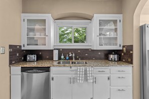 A kitchen with white cabinets, a granite countertop, a stainless steel dishwasher, a sink, and a window with a view of greenery. - Boise-Westend-hot tub-Central location 4 bedrooms (Boise)