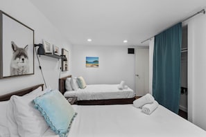Ein Hotelzimmer mit zwei Betten, einem Fuchs Gemälde und einer Strand Szene an der Wand.
