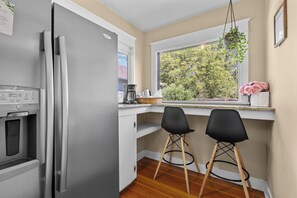 A kitchen with a stainless steel refrigerator, a coffee maker, and a window with a view of trees. - Boise-Westend-hot tub-Central location 4 bedrooms (Boise)