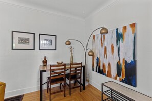 A dining area with a wooden table and chairs, a vase with dried flowers, and a large abstract painting on the wall. - Boise-Westend-hot tub-Central location 4 bedrooms (Boise)