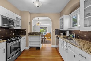 A modern kitchen with stainless steel appliances, a granite countertop, and a view to the dining area.
