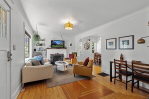 Ein modernes Wohnzimmer mit Kamin, Fernseher und Essbereich mit Holzkunst.