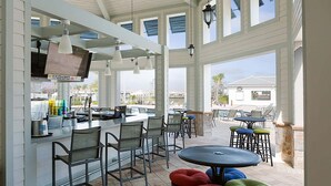Een overdekt terras met tafels en stoelen, een bar en uitzicht op het strand.
