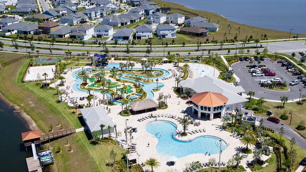Luchtbeeld van een resort met meerdere zwembaden, een strand en een parkeerplaats.