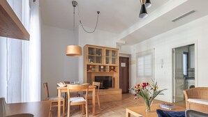 Un salon moderne avec une table à manger en bois, des chaises, un canapé, une table basse et une cheminée.