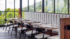 A restaurant with a view of a forested mountain range, large windows, and modern furniture. - Munduk Cabins by Desa Hay (Munduk)