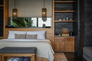 Un dormitorio con cama, banco, estanterías de madera y ventana con vistas.
