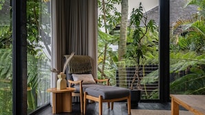 A room with a large window, a chair, a small table, and a potted plant. - Munduk Cabins by Desa Hay (Munduk)