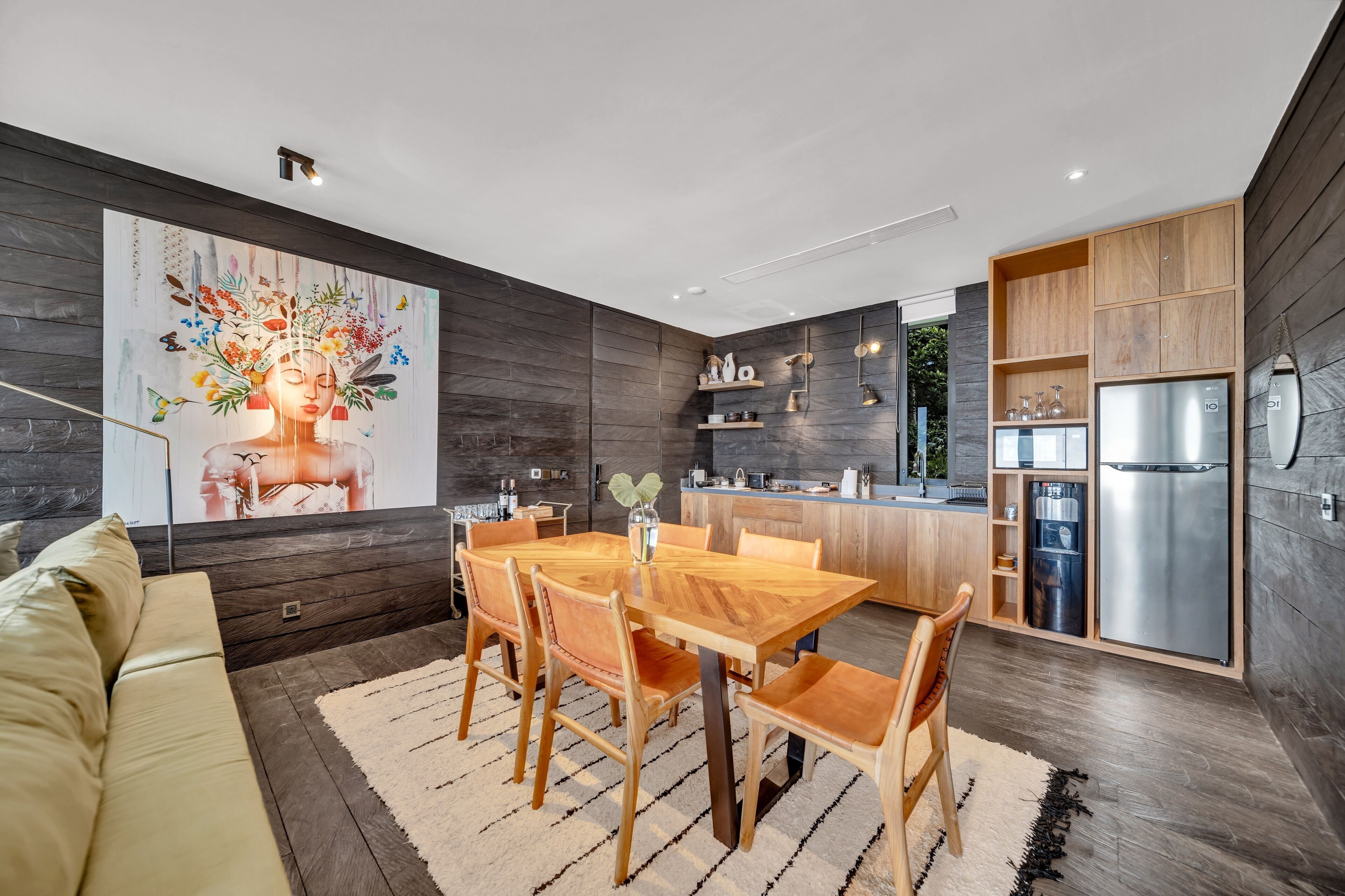 A modern kitchen with wooden cabinets, a stainless steel refrigerator, and a dining area with a wooden table and chairs.