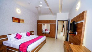 Habitación de hotel moderna con una cama grande, armario de madera y televisor de pantalla plana.