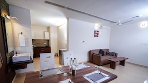 Una sala de estar moderna con un sofá marrón, una mesa de centro de madera y un comedor con una mesa de madera dispuesta para cuatro.