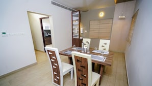 Un comedor con una mesa de madera, sillas blancas y un separador decorativo.