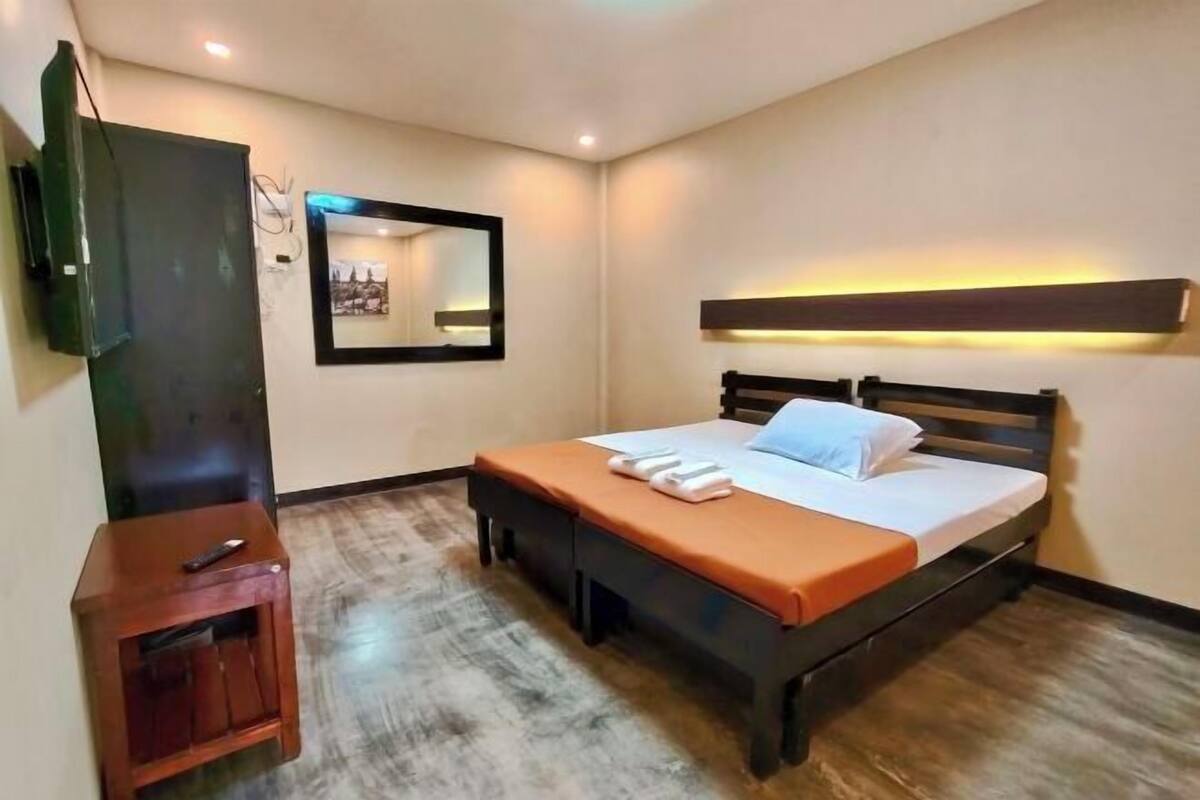 Une chambre à coucher avec un lit, une table de chevet, une télévision et un miroir.