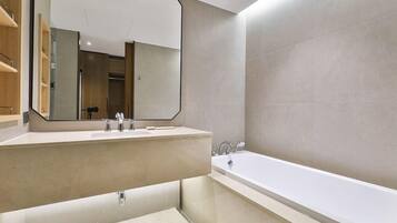 A modern bathroom with a large mirror, two sinks, and a bathtub.