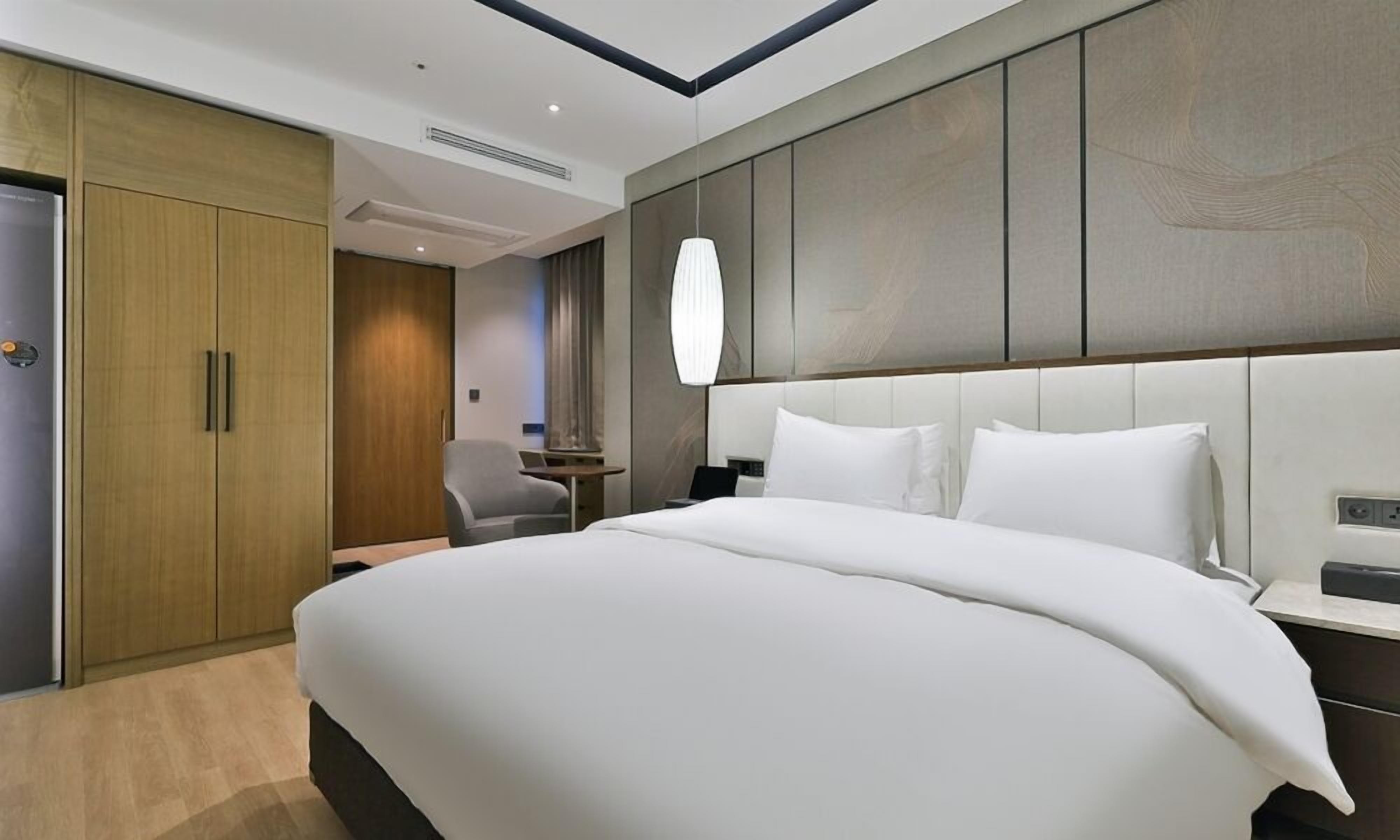 Una habitación de hotel moderna con una cama grande, un escritorio y un armario.
