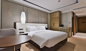 A modern hotel room with a bed, bedside table, lamp, and a desk with a chair. - Daegu Billion Western Hotel (Daegu)