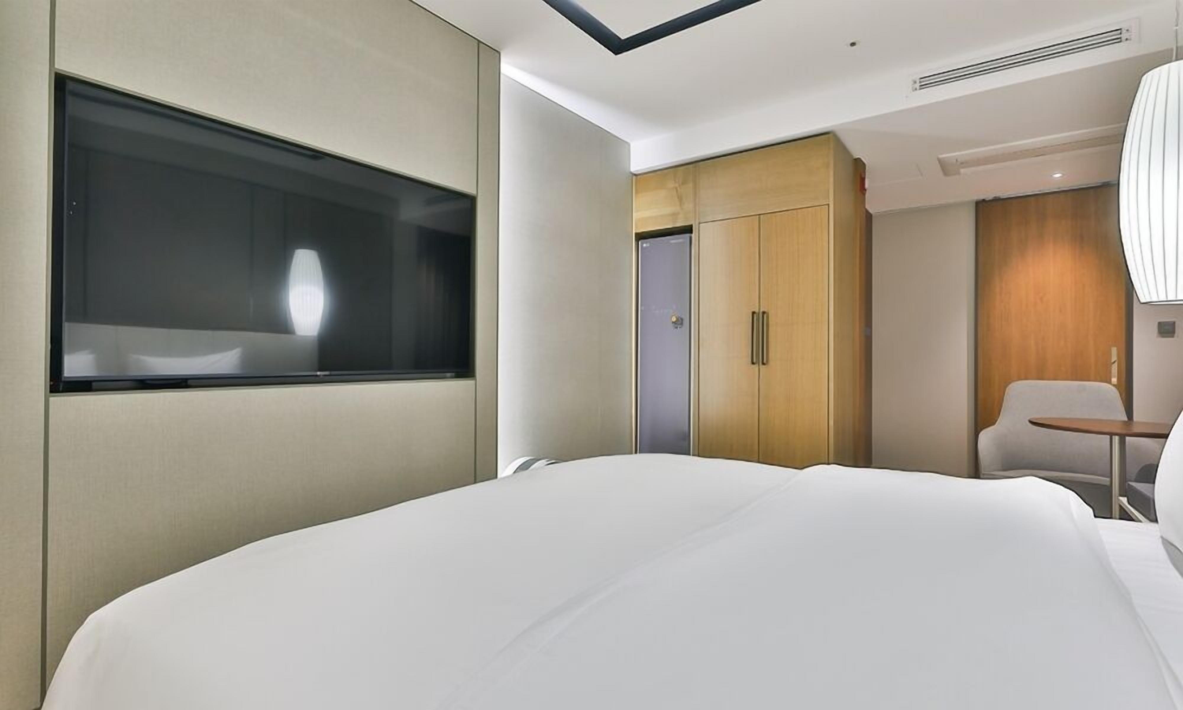 Una camera d'albergo moderna con un letto grande, una finestra, un armadio, una scrivania e una sedia.