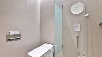 A modern bathroom with a glass shower enclosure, a toilet, and a control panel.