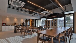 Un comedor amplio con una larga mesa de madera y sillas, ventanas grandes con vistas a la ciudad, y modernas lámparas.