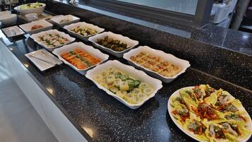 Buffet com diversos pratos, incluindo massas, saladas e frutos do mar.