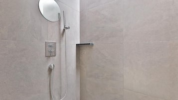 A bathroom with a shower, a mirror, and a control panel.