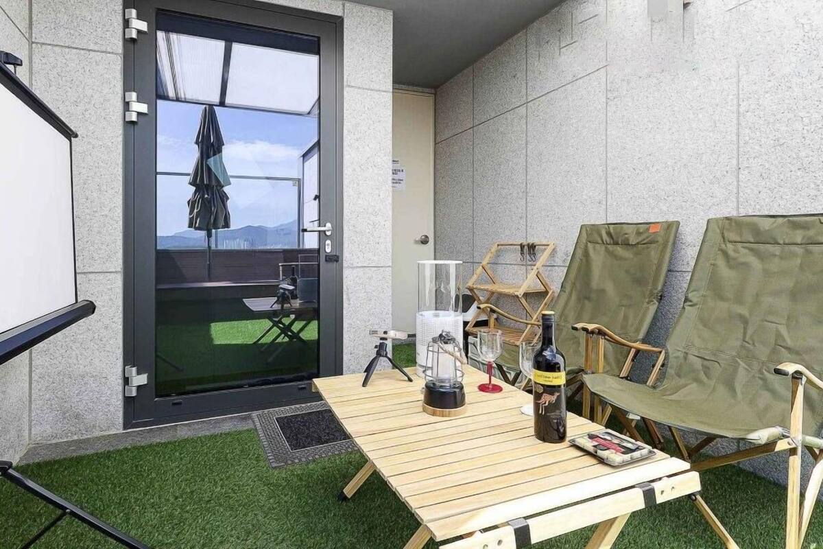 Un balcon équipé d’une table, de chaises, d’un écran de projection et offrant une vue sur l’extérieur.