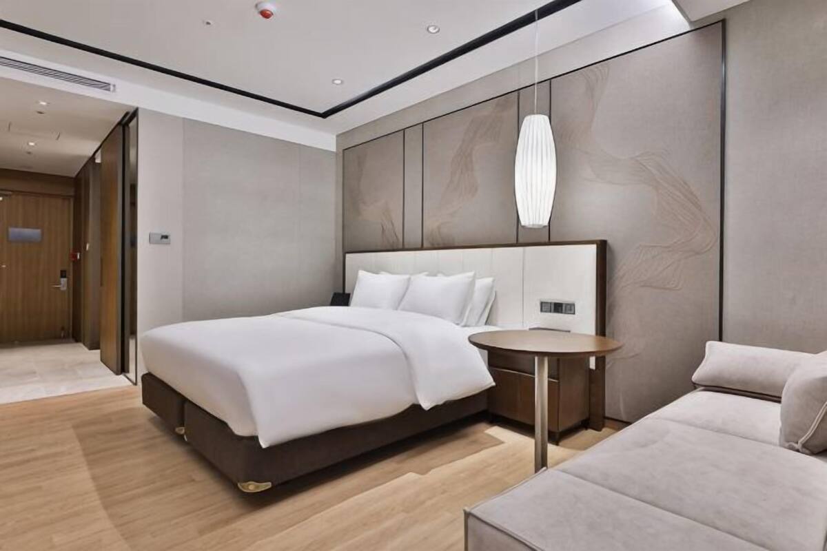 Une chambre d’hôtel moderne avec un grand lit, une table de chevet et un canapé.