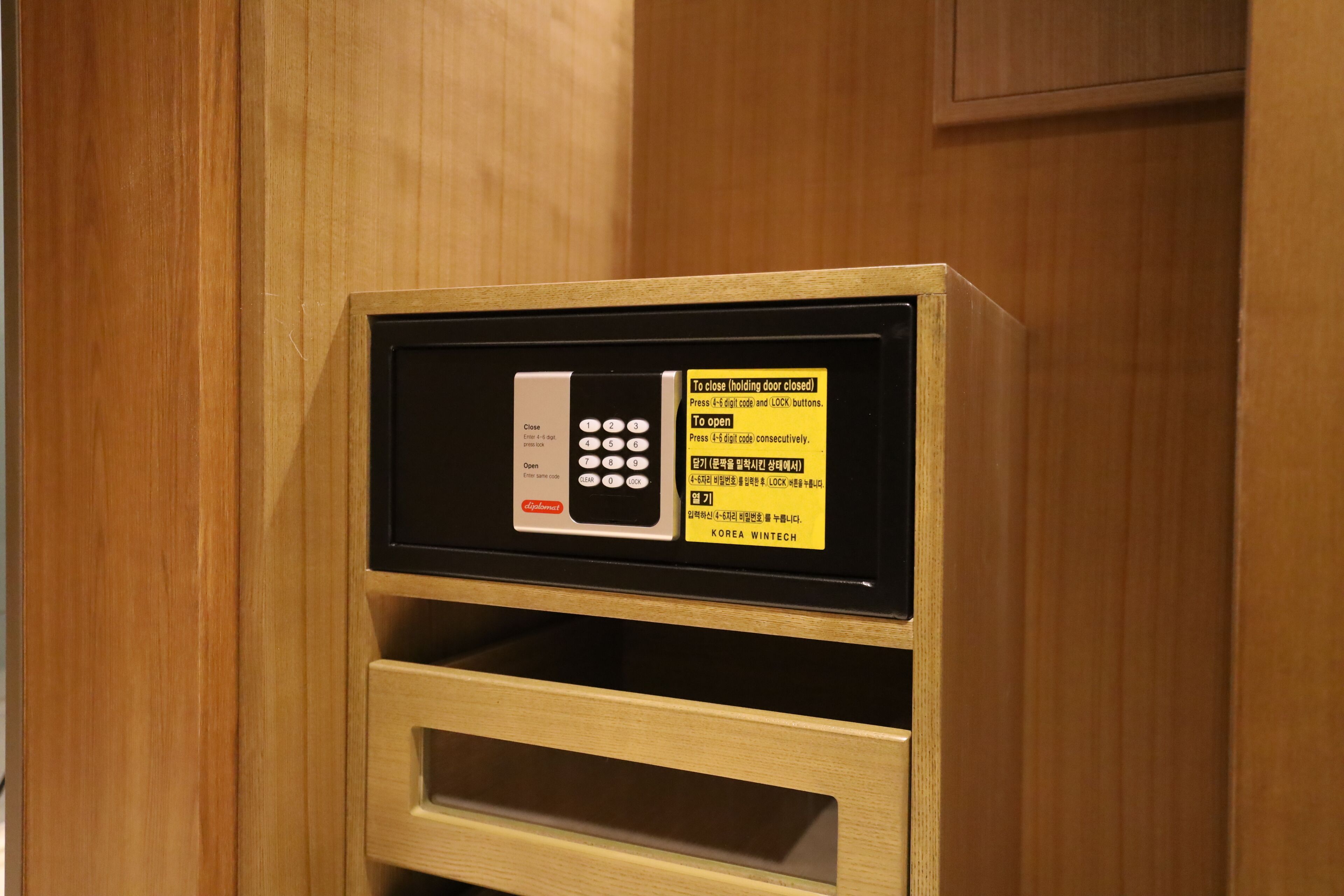 Un mueble de madera con cerradura electrónica integrada y un cajón pequeño.