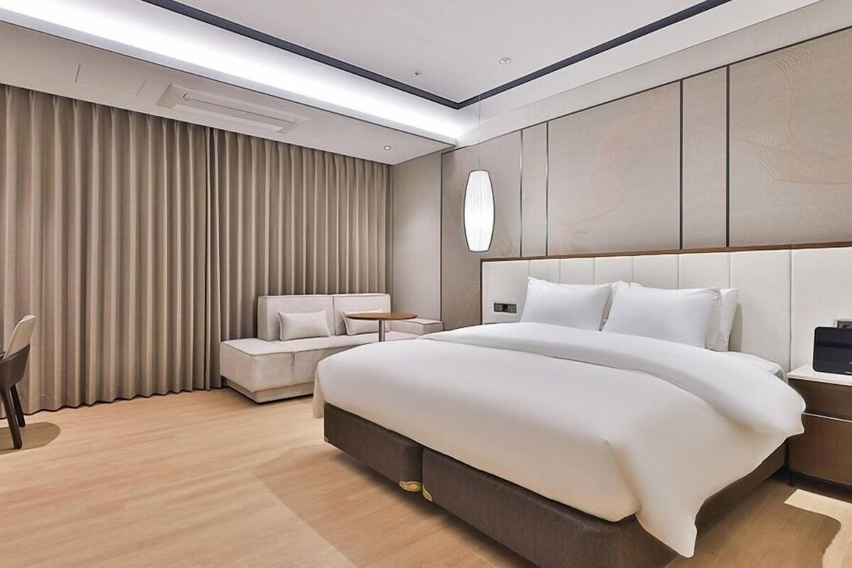 Une chambre d’hôtel moderne, dotée d’un grand lit, d’un bureau et d’un coin salon.