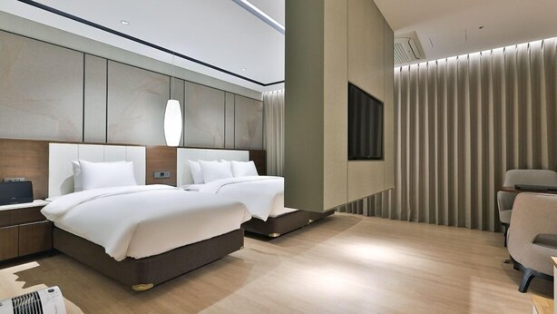 Una habitación de hotel moderna con una cama grande, mesitas de noche, un escritorio y una silla.