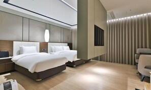 Een moderne hotelkamer met een groot bed, nachtkastjes, een bureau en een stoel.