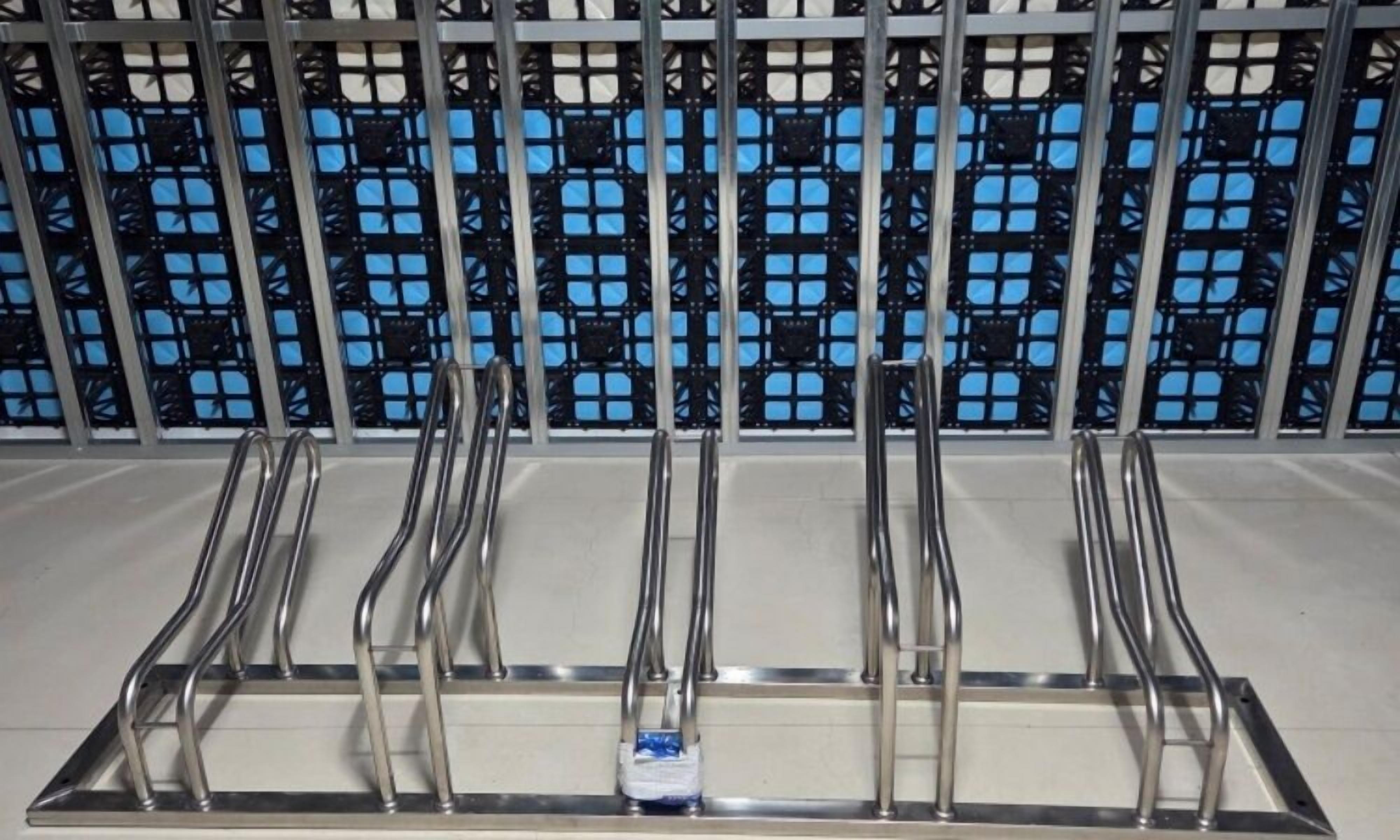 A metal rack with multiple handles, likely for luggage, against a wall with a blue and black patterned design.