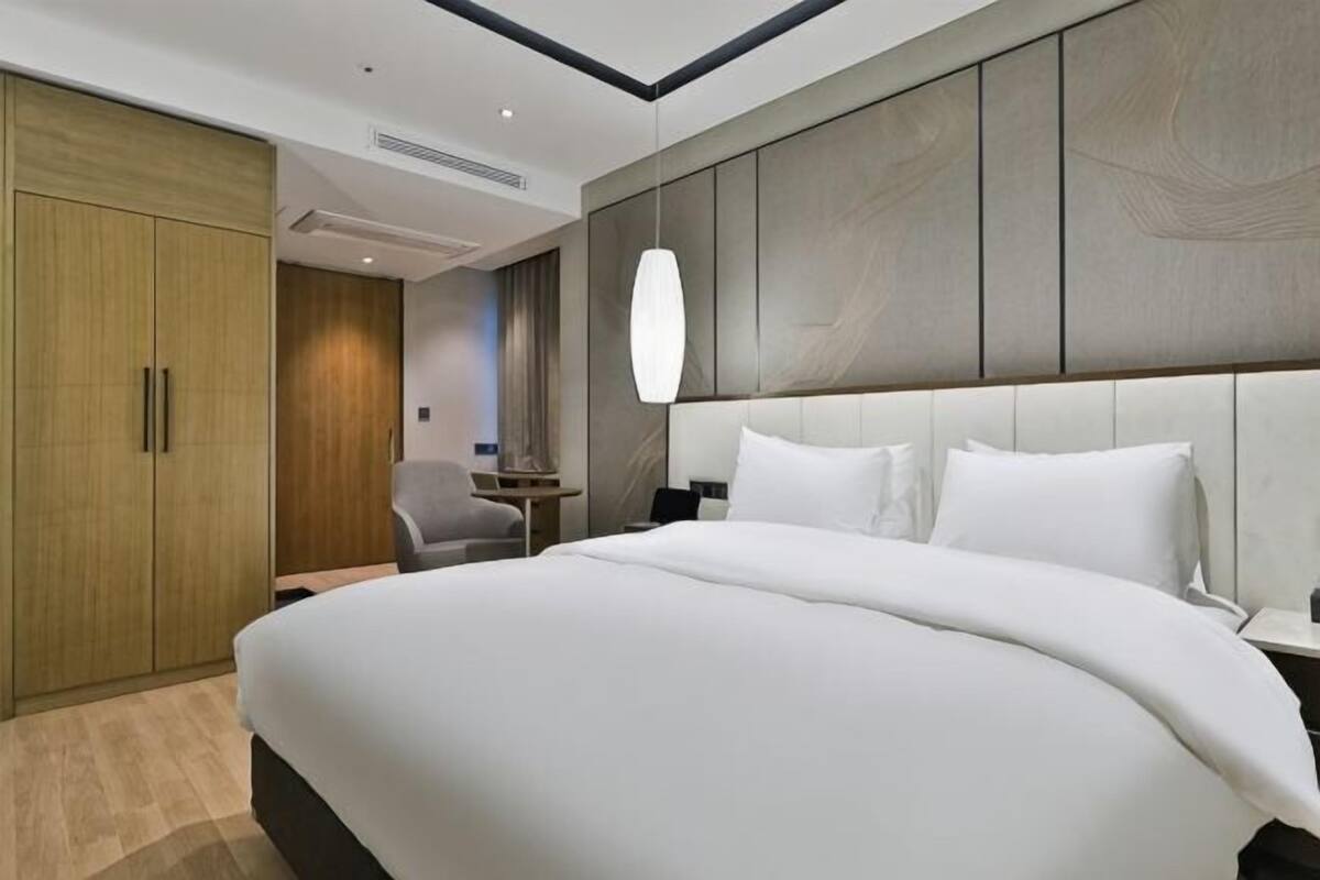 Une chambre d’hôtel moderne, dotée d’un grand lit, d’un bureau et d’une armoire.