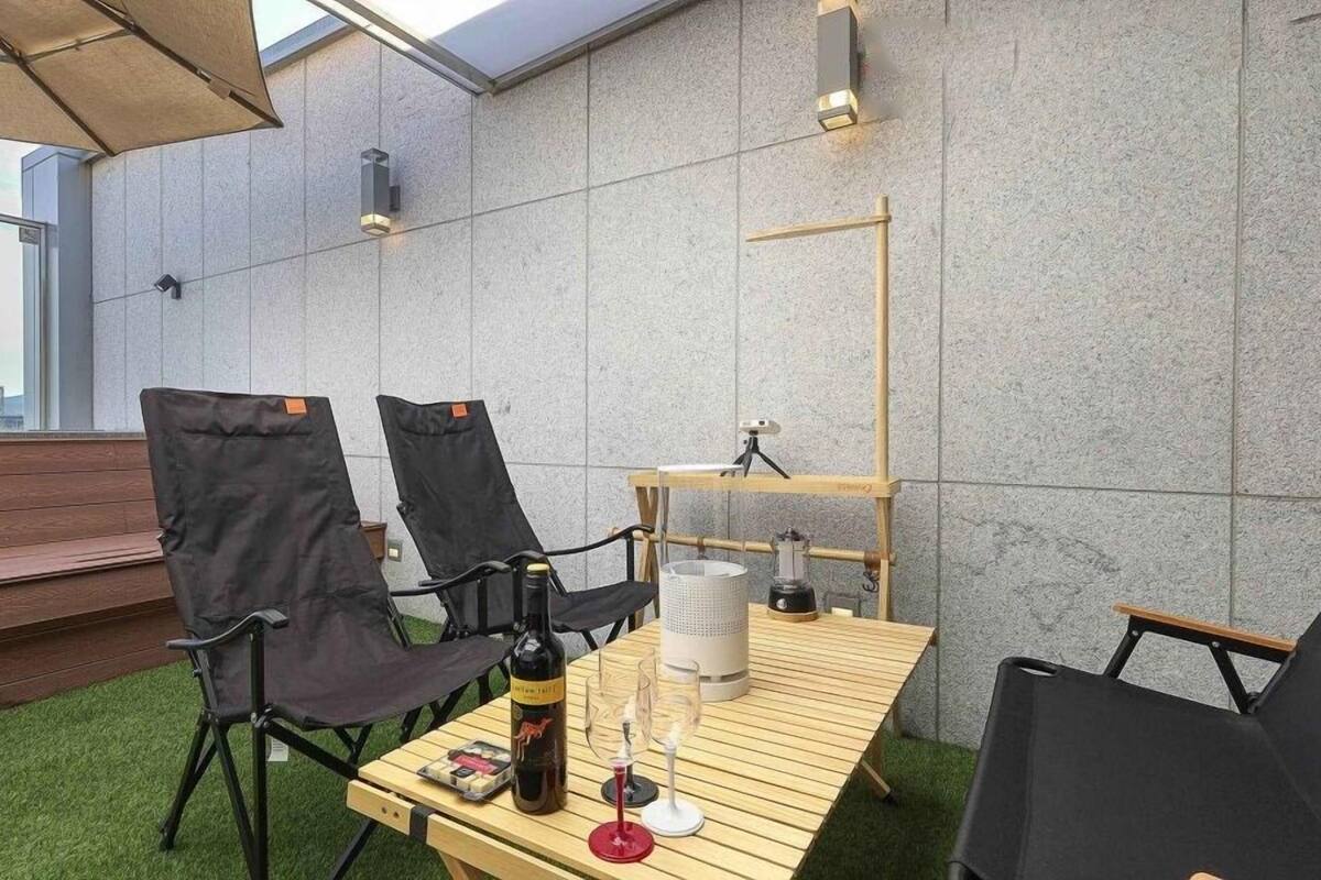 Une terrasse sur le toit avec une table en bois, deux chaises, une bouteille de vin et un trépied.