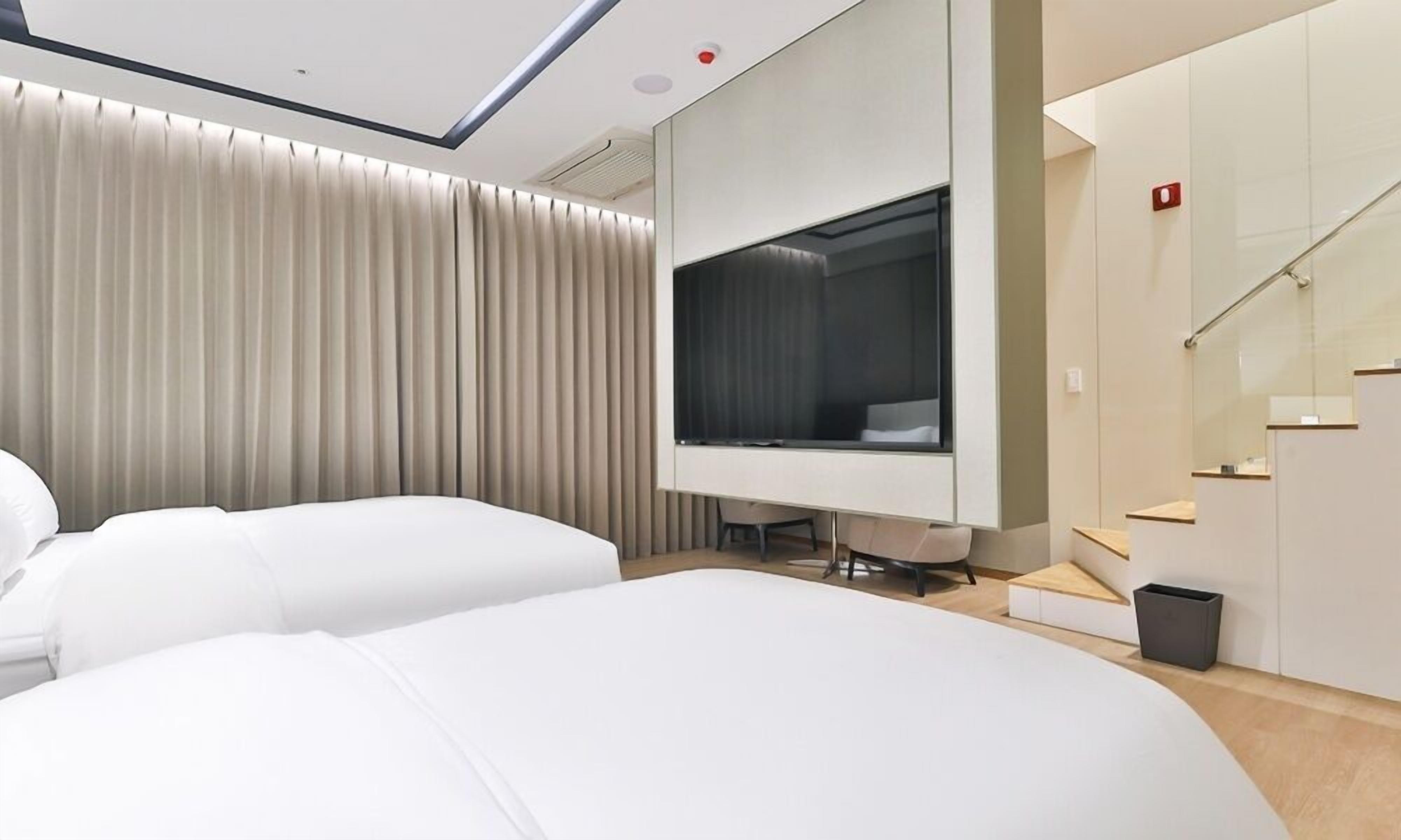 A modern hotel room with a large bed, a desk, and a television.