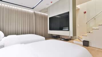 A modern hotel room with a large bed, a desk, and a television.