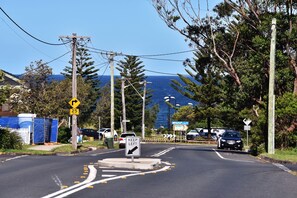 A road with a roundabout, traffic signs, and a view of the ocean. - Point Bulli (Bulli)