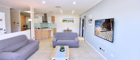 A modern living room with a sofa, a coffee table, and a painting of a beach scene.
