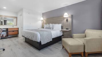 Una habitación de hotel moderna con una cama grande, lámparas de noche, un sofá y una mesita de noche de madera.