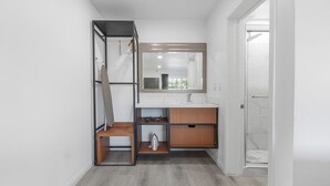A bathroom with a shower, a sink, and a mirror. -  Inland Inn & Suites (San Bernardino)
